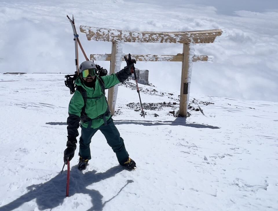 Guia de montanhismo e snowboarding e esqui no Japão usando roupas verde de inverno, representando expedições guiadas de montanhismo, esqui e snowboard nas montanhas japonesas.