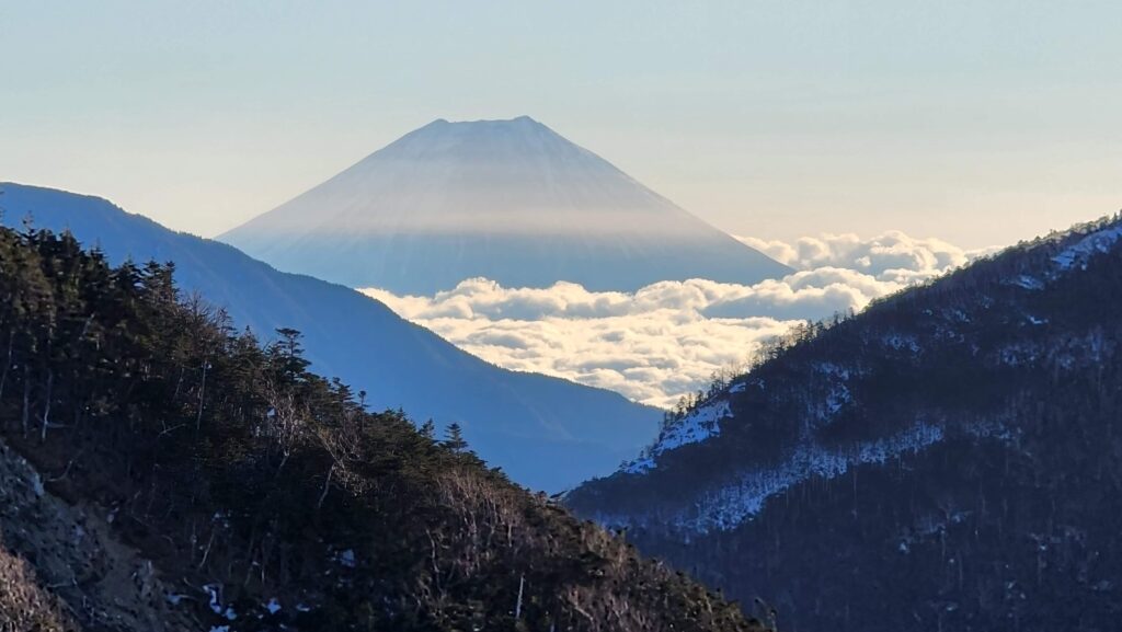 Vista panorâmica do Monte Fuji e outras montanhas do Japão de um cume com nuvens, representando a experiência de montanhismo e escalada com guia no Japão.