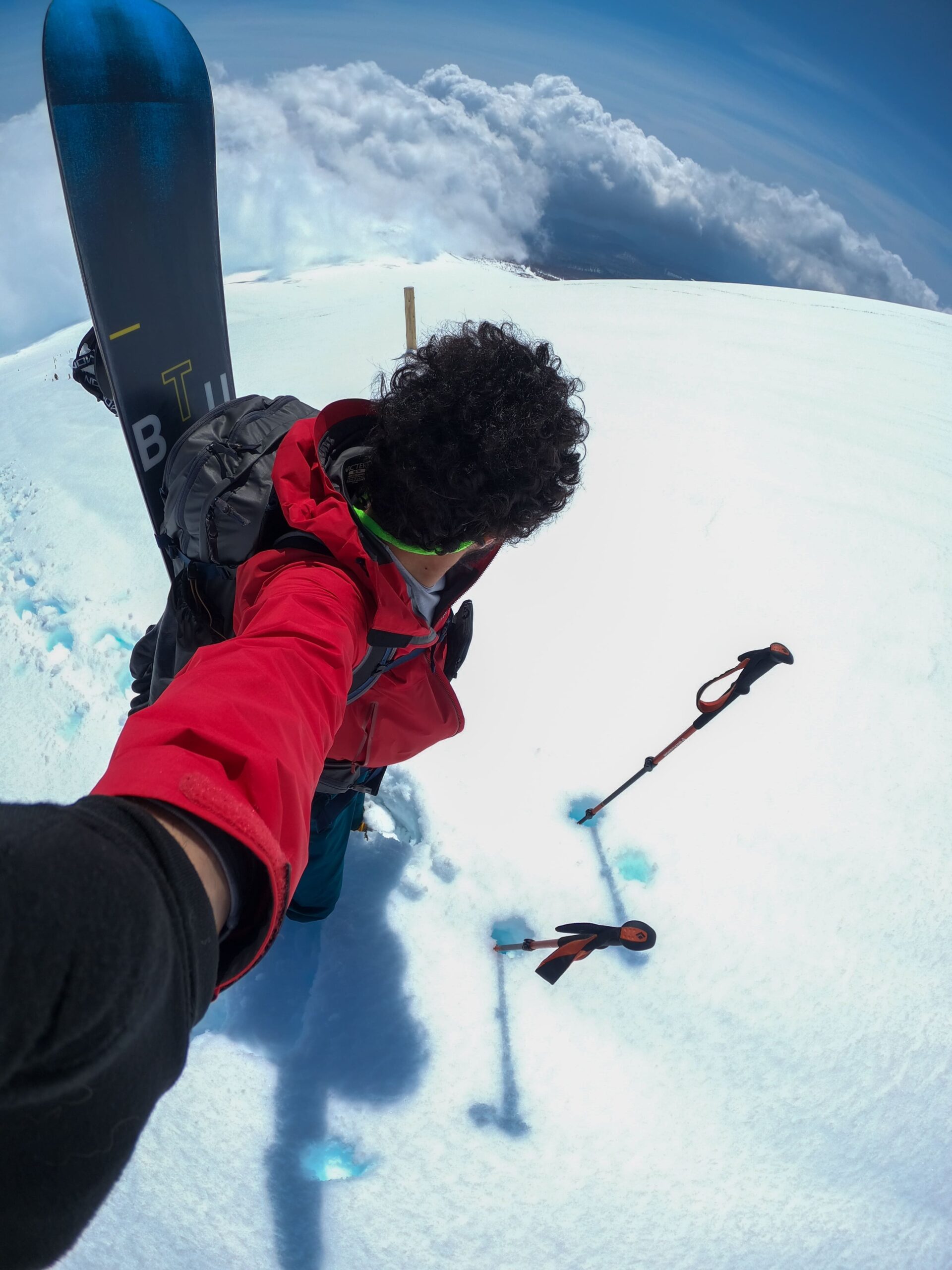 Guia de montanhismo, snowboarding e esqui Daniel Tamaki no Japão usando roupas vermelhas de inverno, representando expedições guiadas de montanhismo, esqui e snowboard nas montanhas japonesas.
